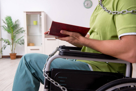 年轻男性残疾人在轮椅上受苦在家