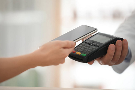 Customer using terminal for contactless payment with smartphone 