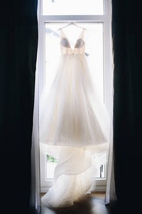 Beautiful detailed wedding dress hanging on the special day 