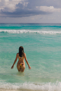 墨西哥坎昆海滩上一个黑发女孩穿着鲜艳的泳装