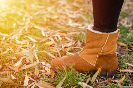 穿着棕色靴子的女孩腿站在草地上。旅行和徒步旅行。