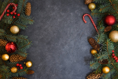圣诞组成的冷杉树枝，圣诞球和糖果，松果。两边都是深色背景。从上往下看