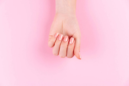 漂亮女人的手。水疗和美甲概念。粉红色指甲的女性手。柔软护肤概念。美容指甲。米色背景