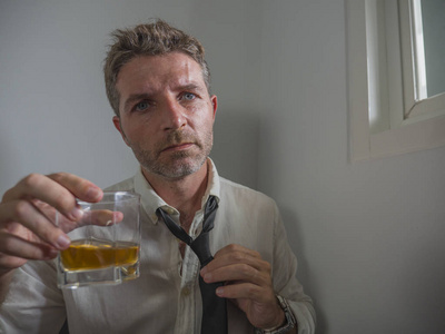 分岁酒30到40岁的酒鬼在失去领带喝酒绝望地拿着威士忌酒杯深思熟虑