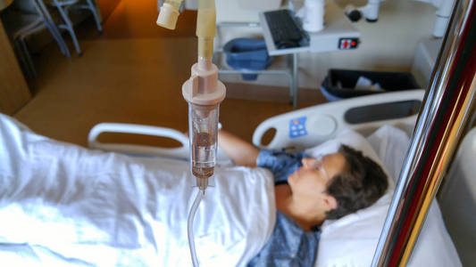 Close up view of an IV drip with female patient out of focus in 