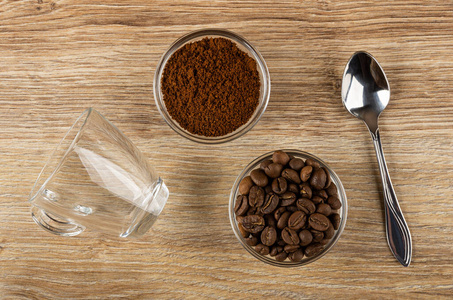empty cup, bowls with ground coffee, coffee beans, spoon on tabl