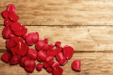 Red rose petals on wooden table 