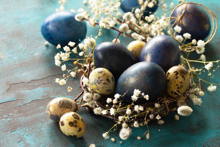 Blue easter eggs in a nest on a blue stone or slate background. 