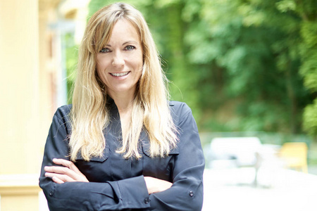 Smiling mature woman with folded arms standing outdoor 