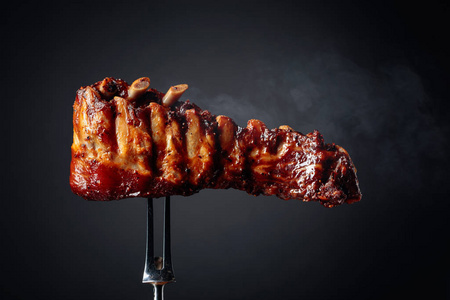 Grilled pork ribs on a fork. 