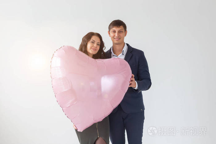 美丽的年轻夫妇，白色背景上有一个心形的气球。情人节。爱的象征