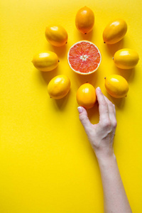 俯视女性手，完整切片的成熟柠檬，黄色表面上呈表盘形状的葡萄柚，健康和维生素的概念
