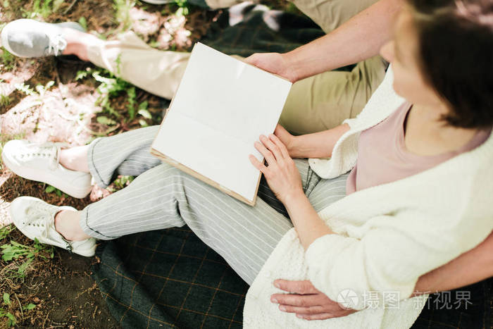 一对夫妇坐在树下看书的特写镜头。