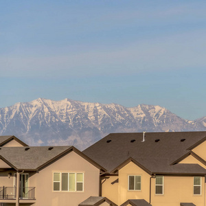 住宅的方形外观，米色墙壁和阳台，紧靠雪山