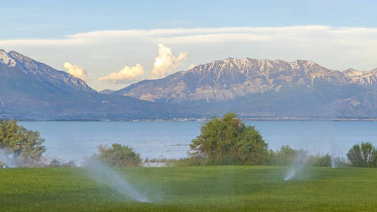 全景框架水从洒水器在绿色草地上的风景自然背景