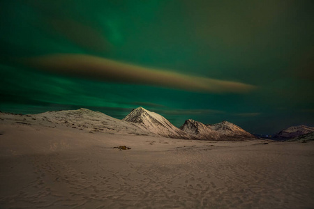 极光，极光和许多云和星星在欧洲北部山脉上空的北极光Tromso，挪威.long快门速度。