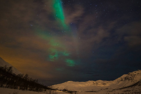 极光，极光和许多云和星星在欧洲北部山脉上空的北极光Tromso，挪威.long快门速度。