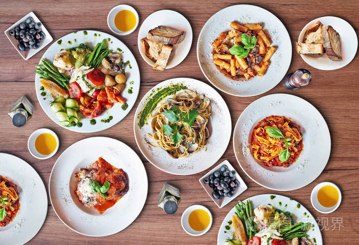 几盘美味的意大利菜摆在有纹理的桌子上