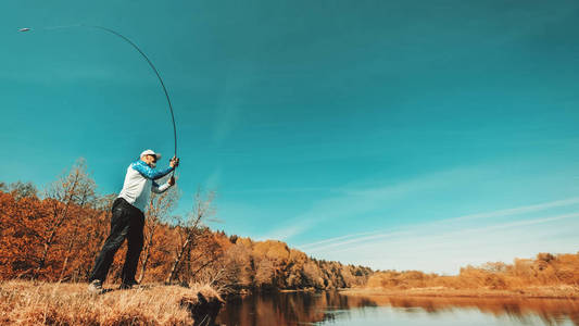 Fisherman with a spinning rod catching fish on a river 