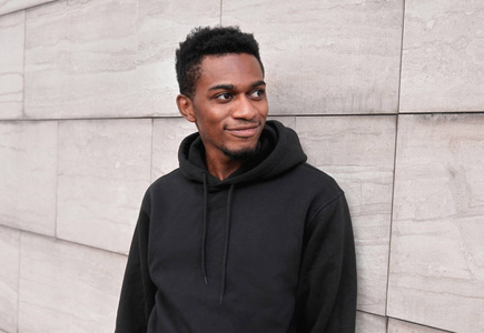 Portrait smiling young african man wearing black hoodie on city 