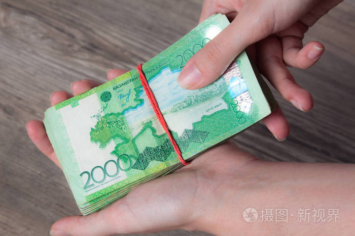 手拿着一沓带着松紧带的钱腾格kzt哈萨克斯坦国家货币kz汇率经济发展