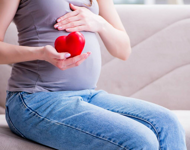 肚子大的孕妇坐在家里的沙发上照片