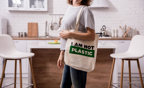 拿着布袋的小女孩。在厨房。我不是塑料。减少塑料袋使用的运动。零浪费
