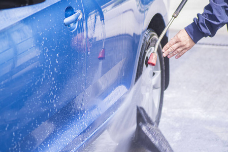在洗车机中使用加压水手动洗车外面。打扫使用高压水的汽车。