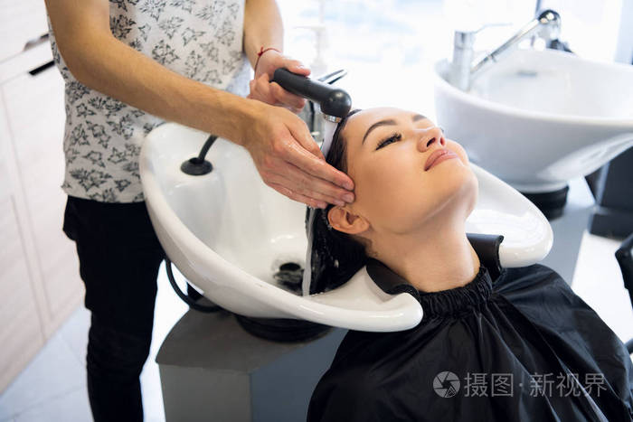 美貌与人的概念快乐的年轻女子与美发师在发廊洗头