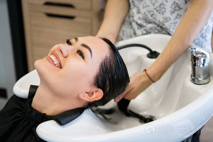 在水疗中心用洗发水,美容院,洗发水进行头发治疗的妇女照片