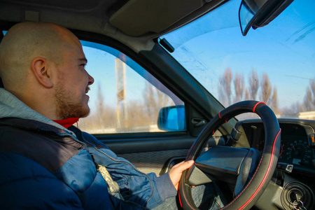 一个年轻人在冬天的路上开车。内部视图