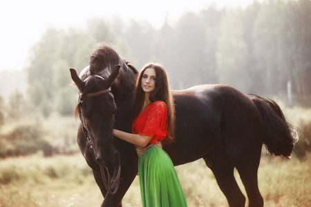 Gypsy girl rides a horse in a field in the summer. A woman with 