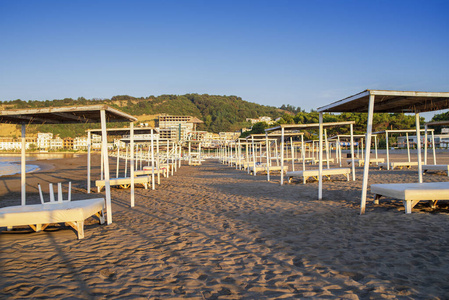 太阳伞和海边的沙滩床海岸。太阳海边有茅草屋顶的床。