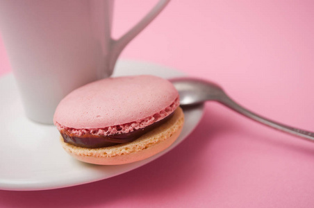 Closeup of french macarons and cup of coffee on pink background 