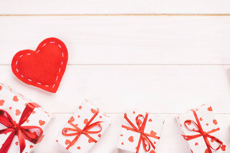 情人节或其他节日手工礼品纸红心和节日包装礼品盒。礼品盒礼物放在白色木质桌面上，带复制空间，空白设计空间