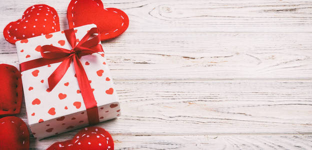 情人节或其他节日手工礼品纸红心和节日包装礼品盒。礼品盒放在白色木质桌面上，带复制空间，设计用空白空间
