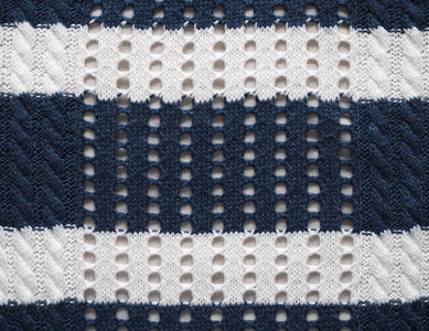 针织面料质感。蓝色和白色。在编织针上编织。组合开孔编织。针织背景。