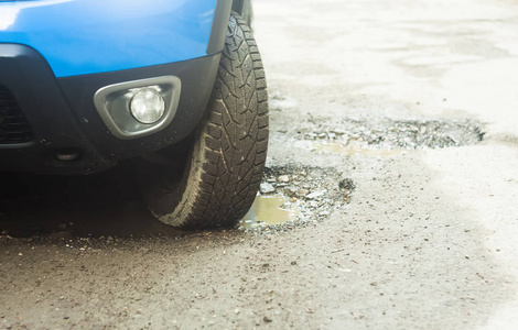 car tire in damaged road with hole in the asphalt. focus on the 