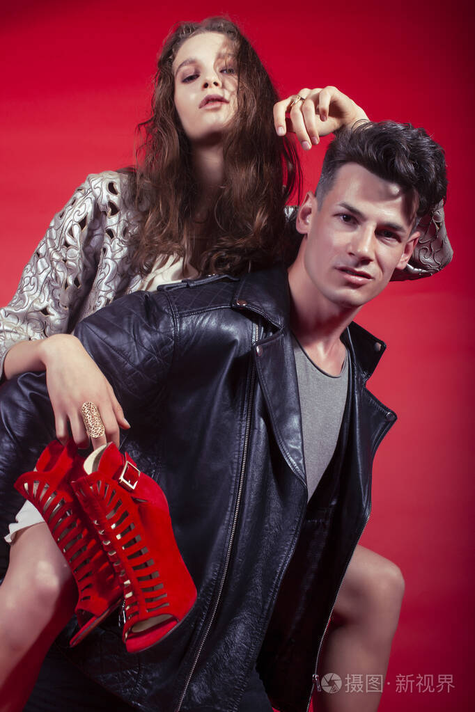 男女女在红色背景下手捧派对鞋摆造型,时尚风格让人眼前一亮照片-正版