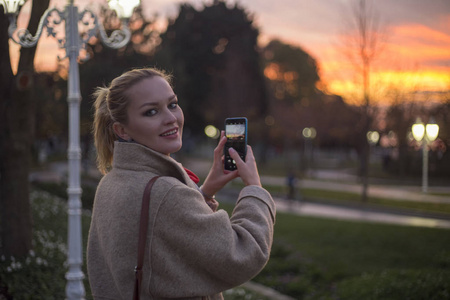 俄罗斯年轻女子日落时用手机拍照