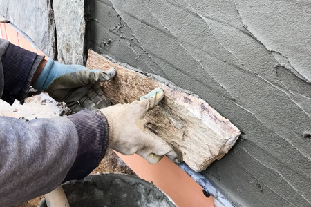 建筑工人用一块粗石面对着房子的地下室。扁平fo