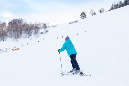 A woman skier slides down the Altai mountain over white snow in 