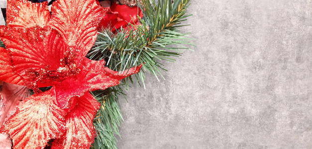 美丽的装饰圣诞和新年快乐的红色一品红组成轻花和松枝在混凝土背景上。大型闪亮庆典背景
