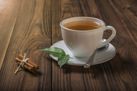 木桌上放着一杯肉桂和绿叶的茶。