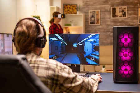 后视图专业视频游戏玩家在强大的个人电脑上玩到深夜在客厅