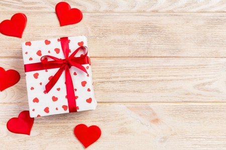 情人节或其他节日手工礼品纸红心和节日包装礼品盒。礼品盒放在橙色木制桌面上，带复制空间，设计用空白空间