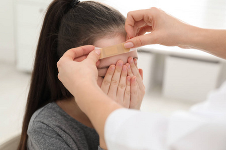 医生在室内给女孩额头贴膏药照片