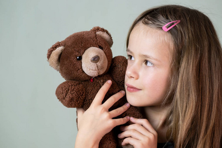 漂亮的小女孩在玩她的泰迪熊玩具。