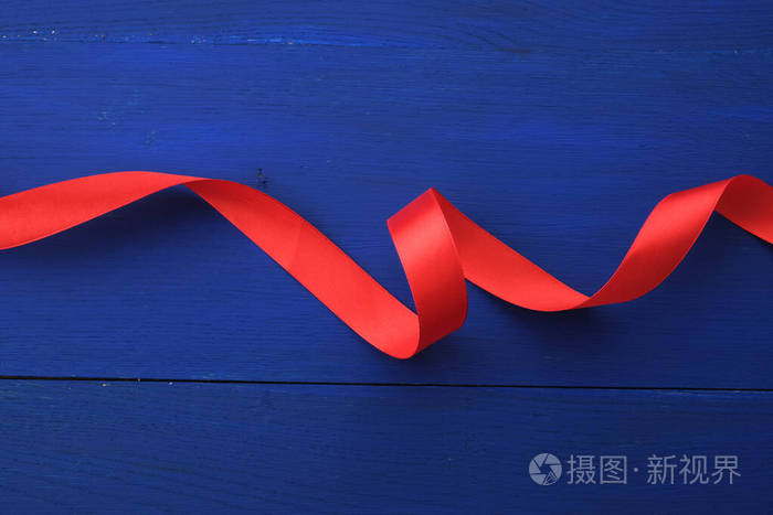 蓝色木质背景上缠绕的红色丝带