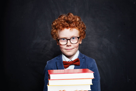 Clever child in primary school uniform and books on blackboard 